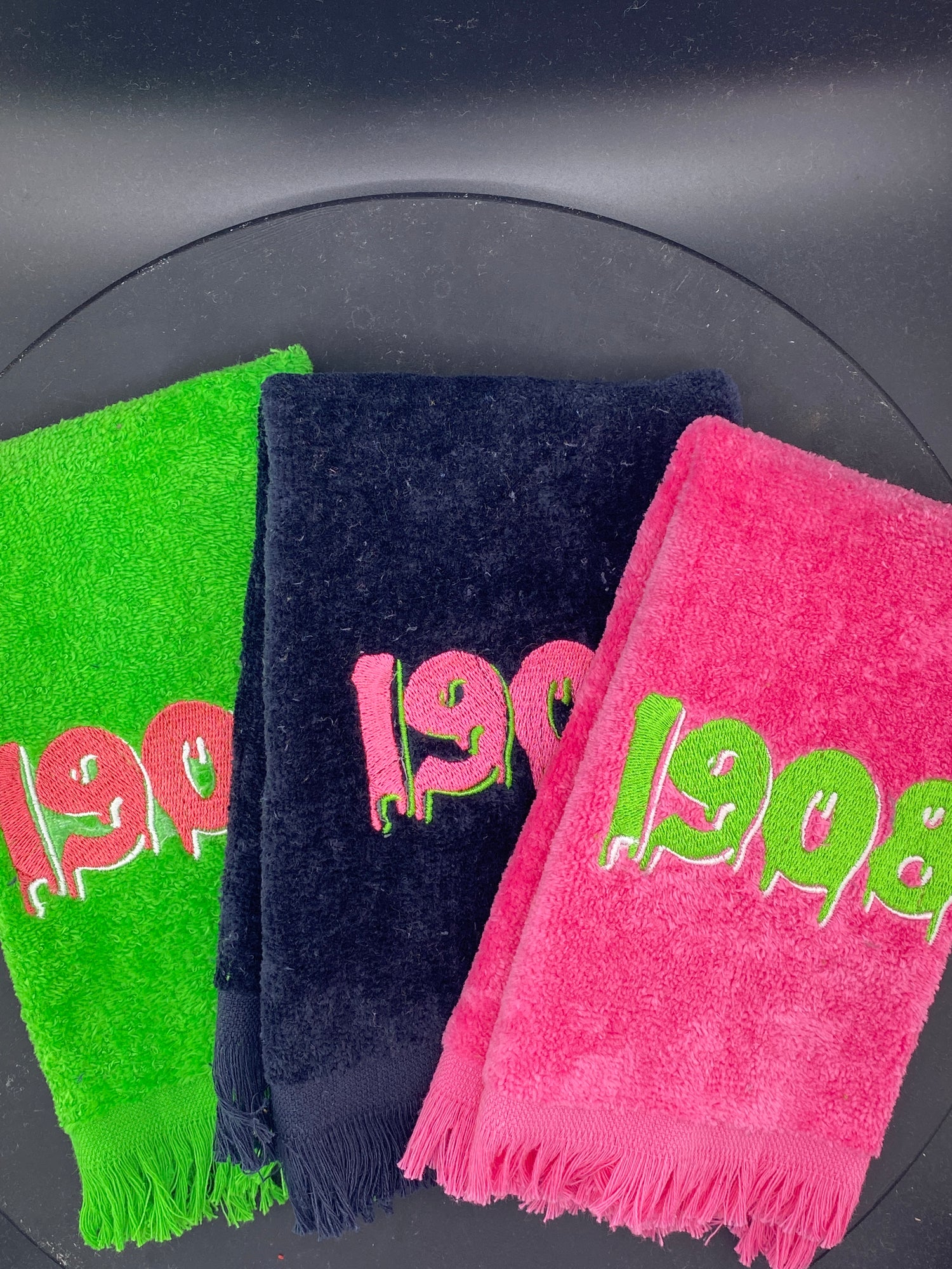 3 plush velour Leisure Luxe Towels in Lime, Azalea, and Black embroidered with a dripping 1908.