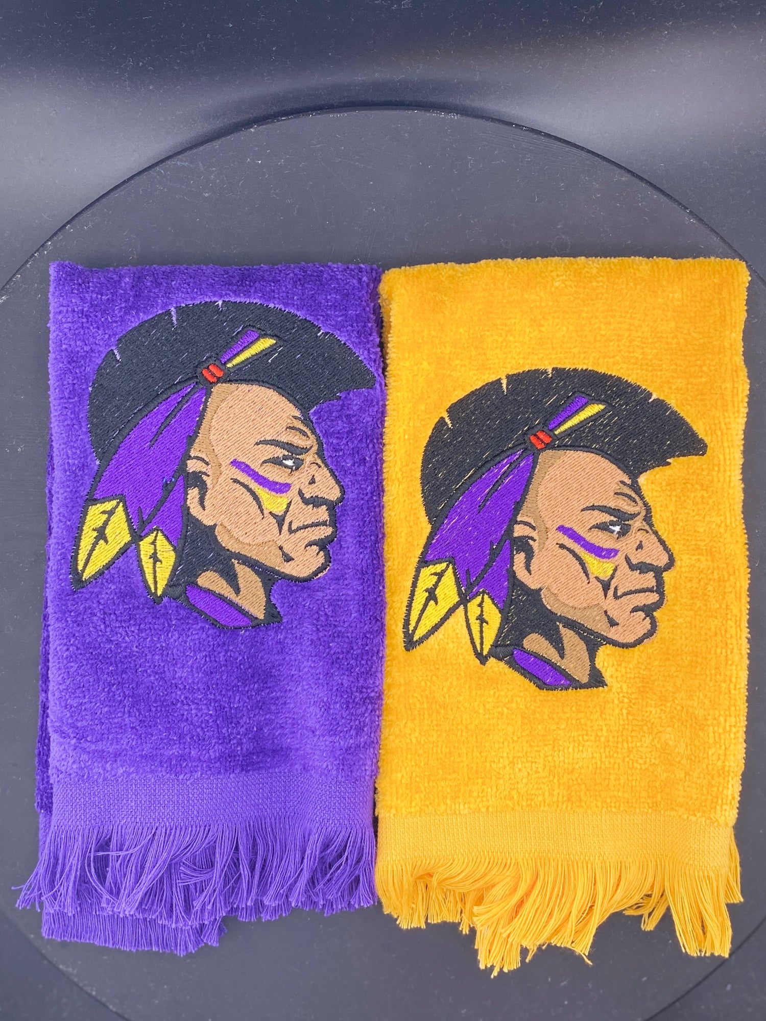 2 plush velour Leisure Luxe Towels embroidered with the Alcorn State University Brave. One towel is purple and the other is gold, they both feature the same personalizable image.