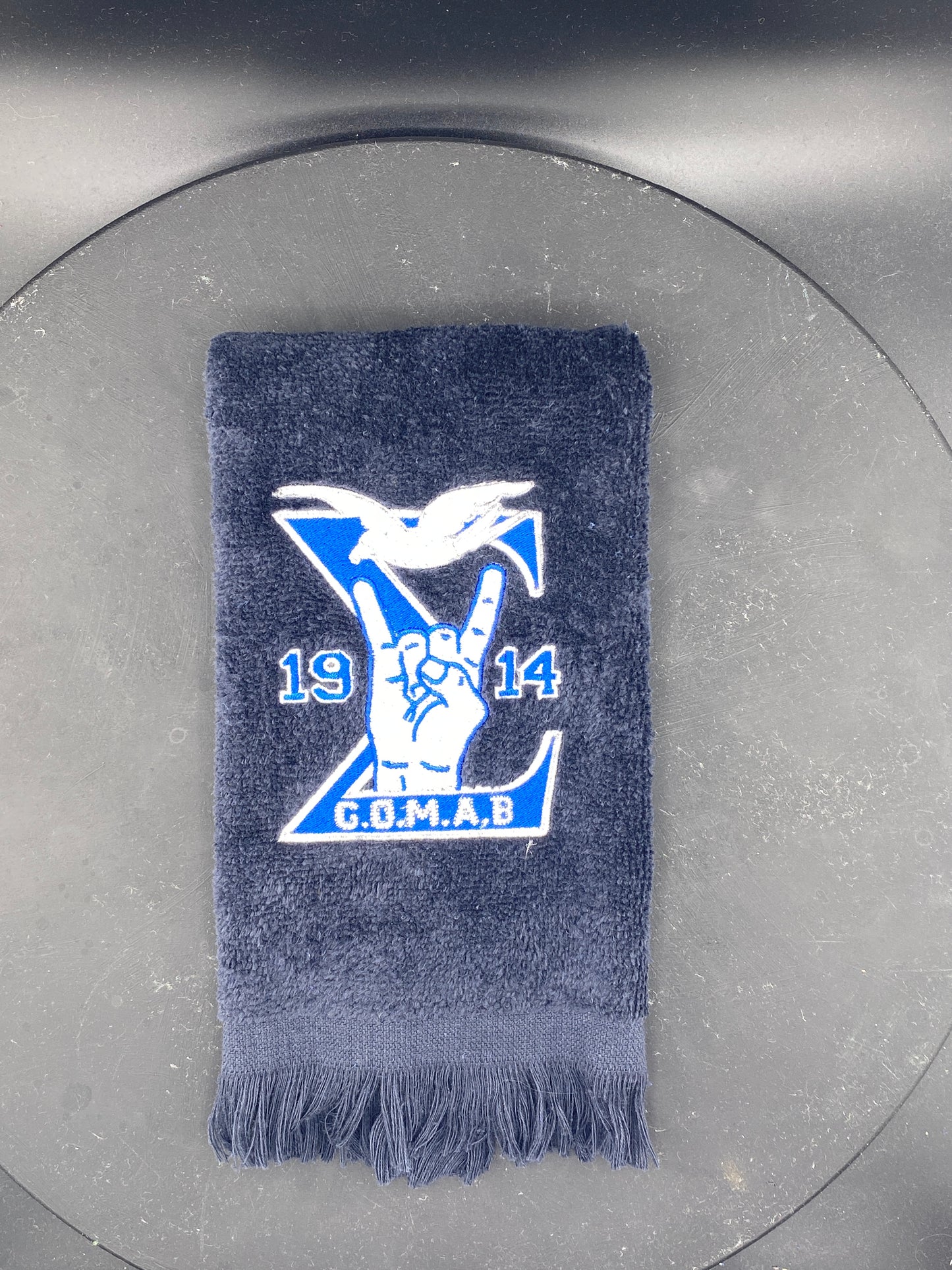 Black Stroll Towel with a Sigma, 1914, handsign, dove and GOMAB embroidered in royal blue, while and silver.