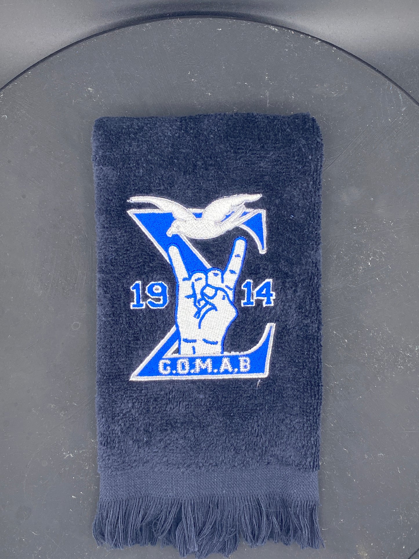 Black Stroll Towel with a Sigma, 1914, handsign, dove and GOMAB embroidered in royal blue, while and silver. 