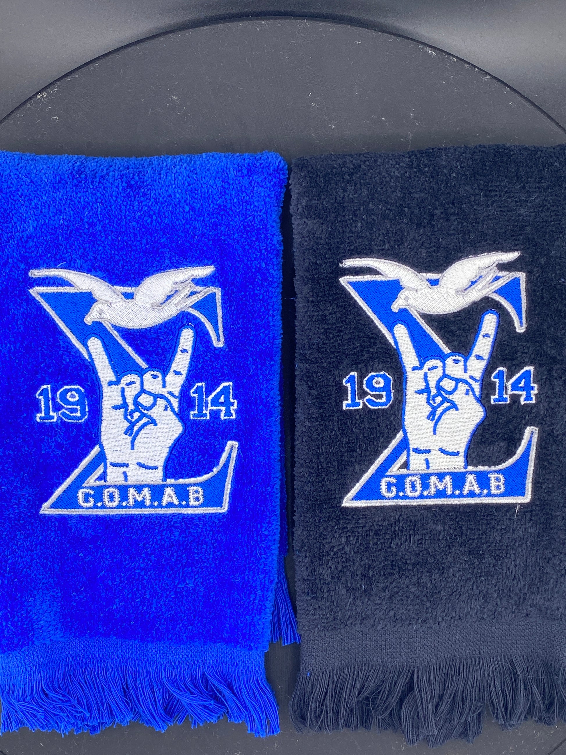Black and royal blue Stroll Towel with a Sigma, 1914, handsign, dove and GOMAB embroidered in while and silver.  