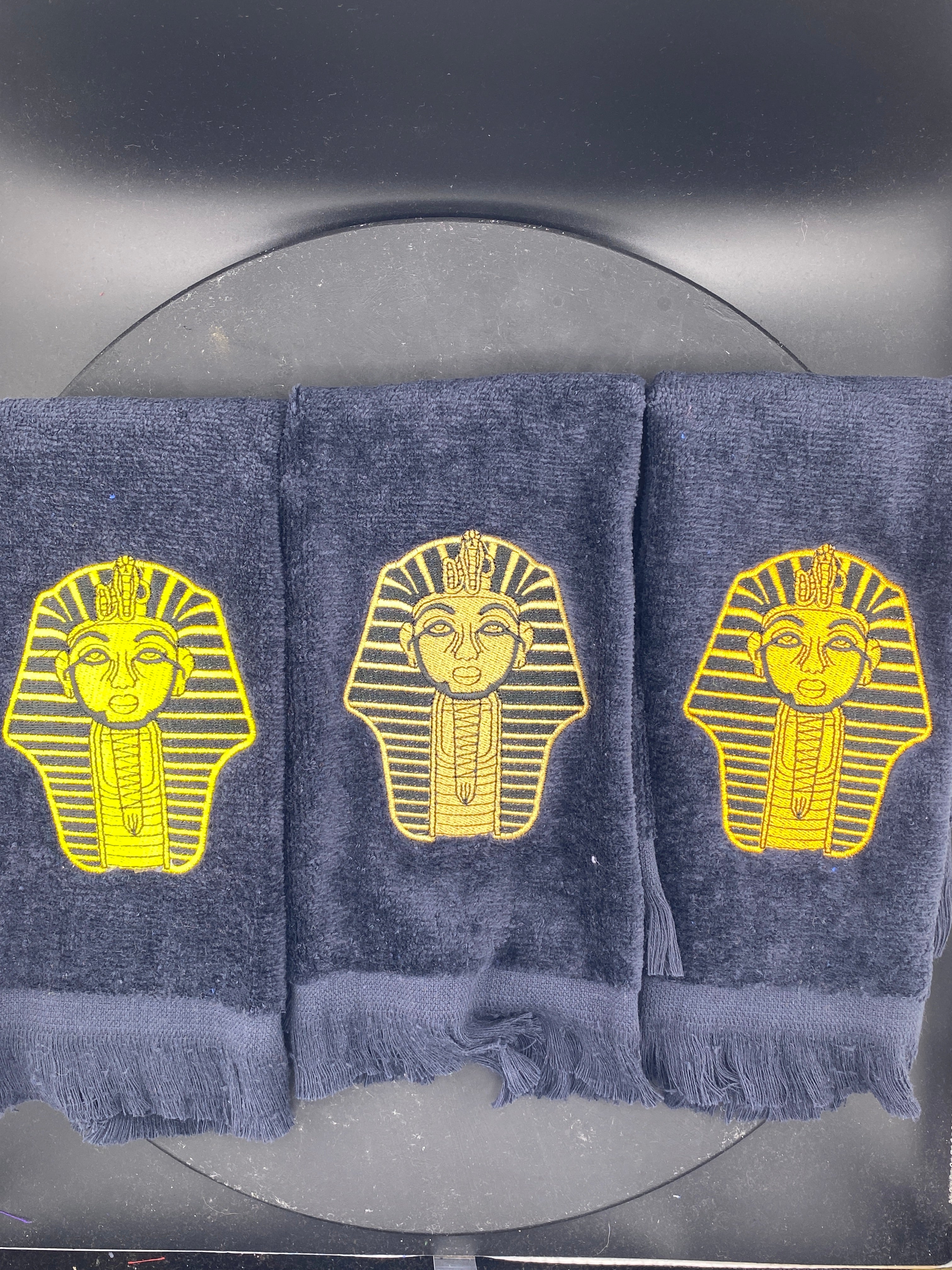3 Alpha Phi Alpha Sphinx Stroll Towels in black stitched in yellow gold, satin gold, and old gold. 