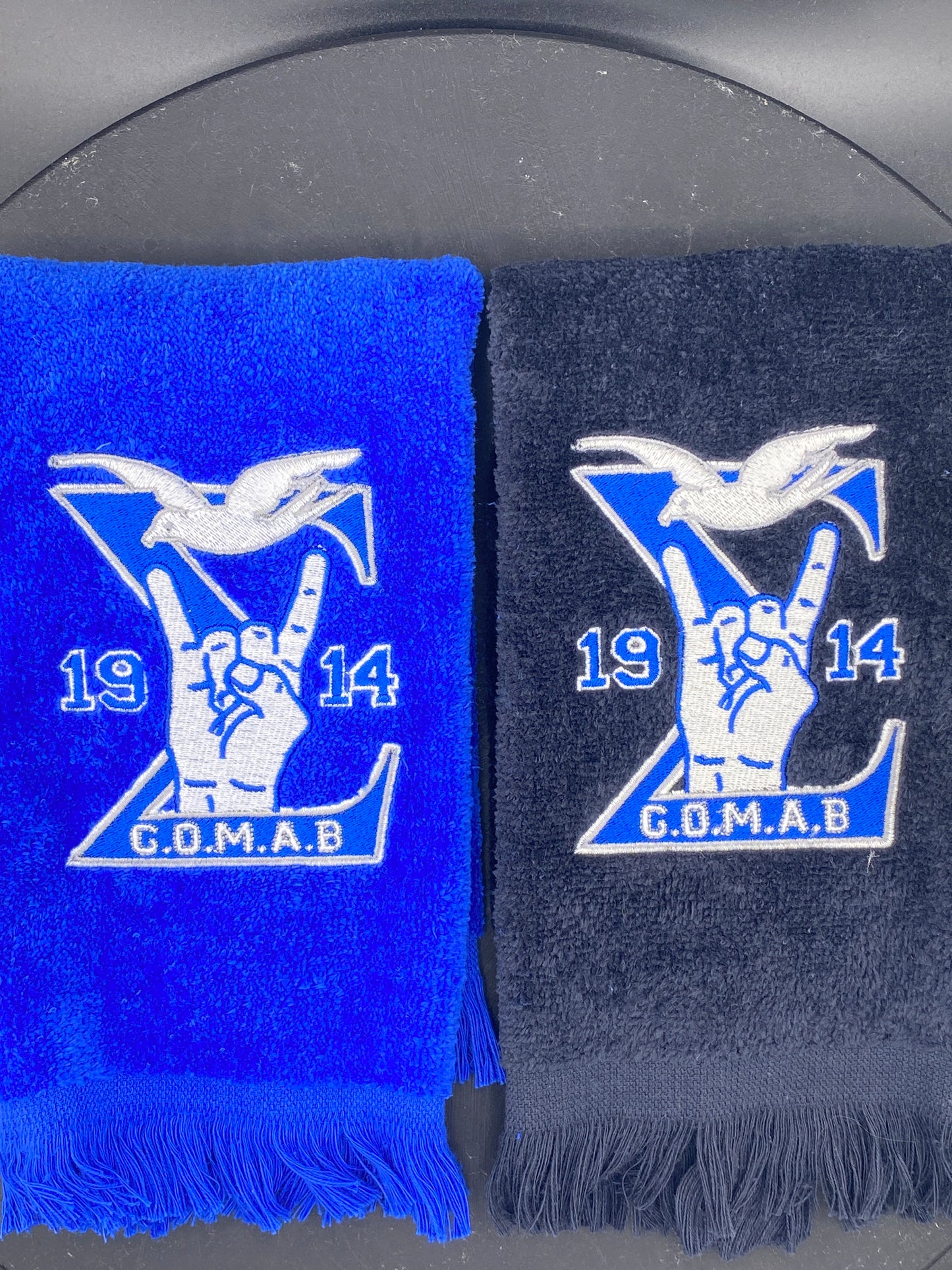 Black and royal blue Stroll Towel with a Sigma, 1914, handsign, dove and GOMAB embroidered in while and silver.  