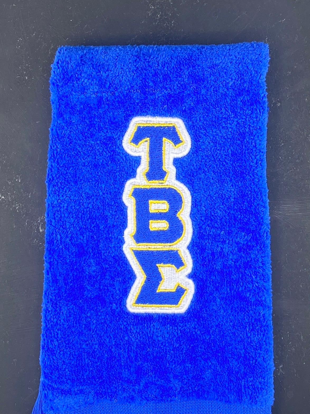 Close Up of Tau Beta Sigma embroidered in white, royal blue and gold on a royal blue Leisure Luxe Towel.  